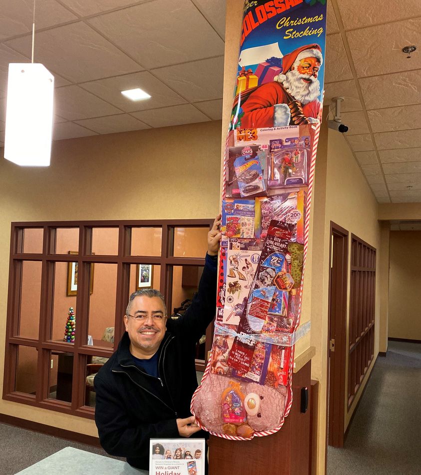 Hughes rep, Oscar, holds up giant holiday stocking