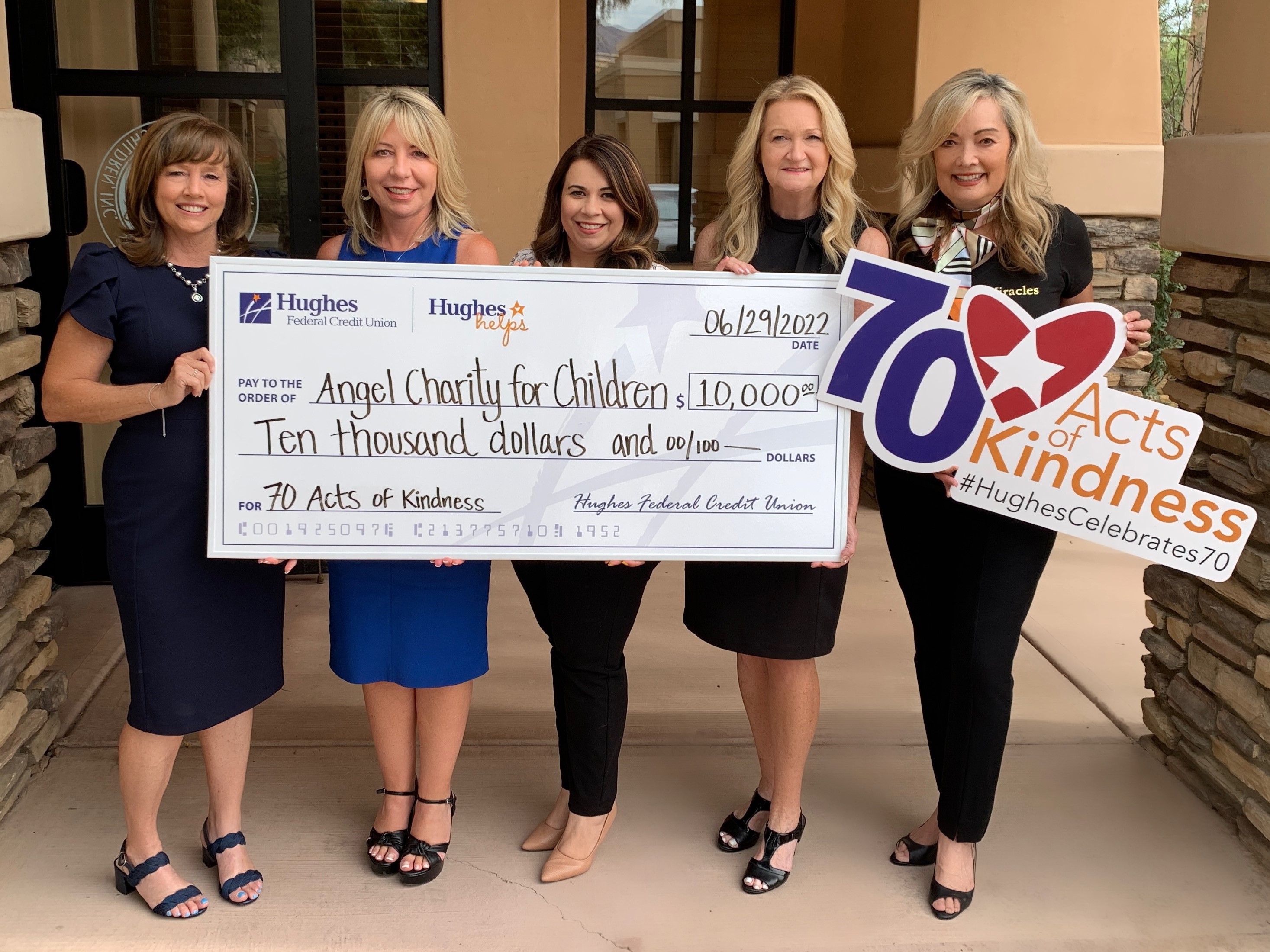 The Angel Charity and Hughes team pose with giant check and 70 acts of kindness sign