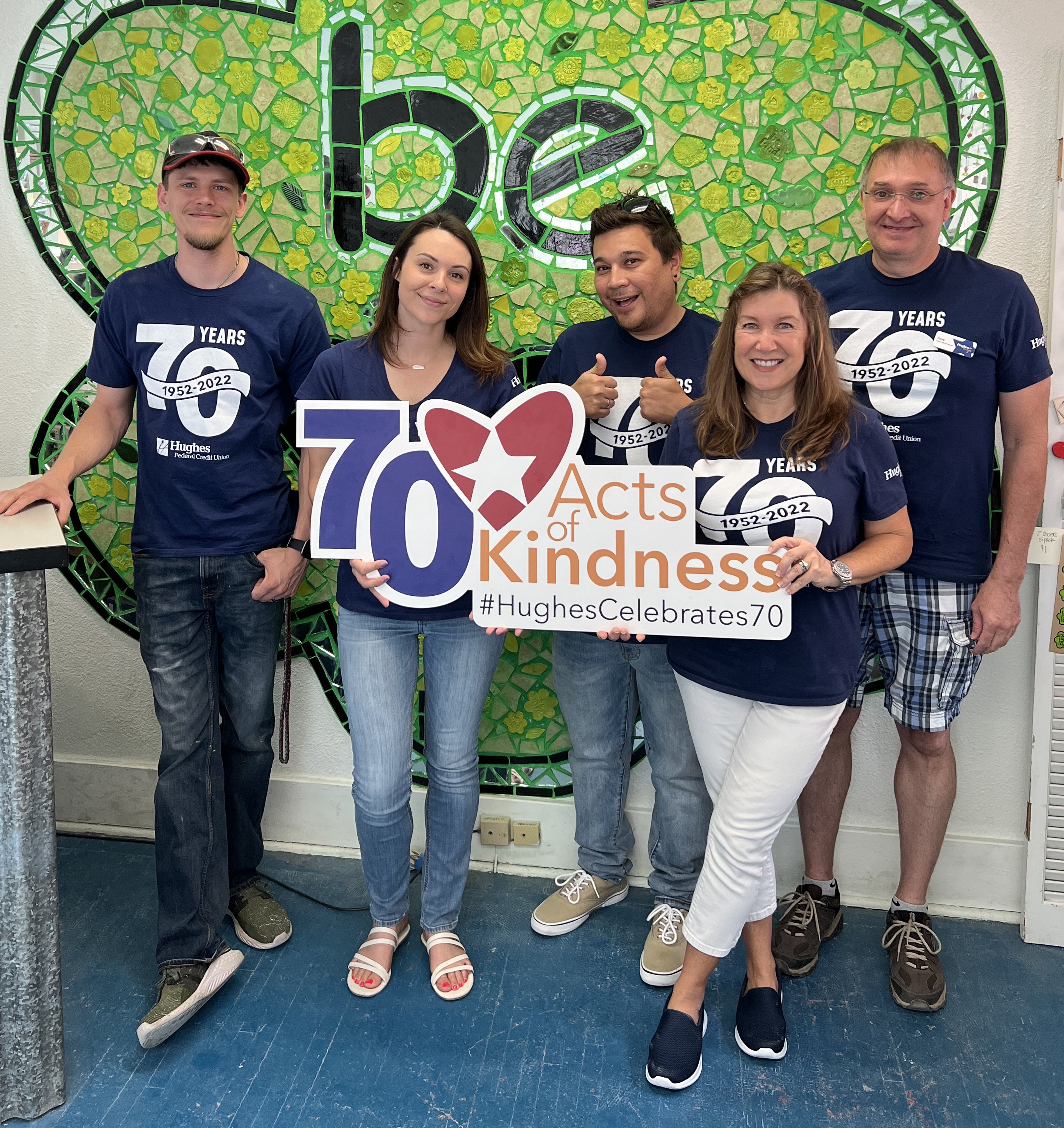 Hughes Team poses in front of Be Kind sign