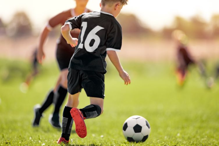 Young boy plays a soccer match on a field.