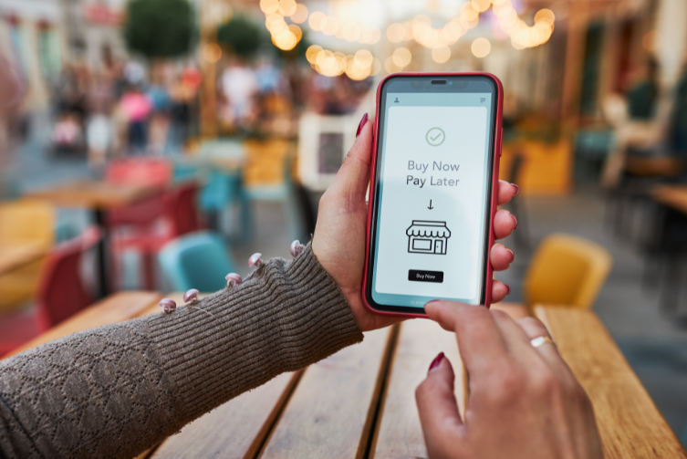 A woman's hand holds a phone with the words, "Buy now, pay later" on the screen.