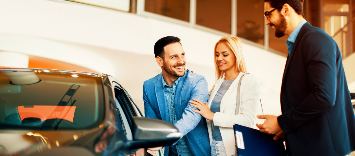 How to find the right auto loan header image - couple at car dealership