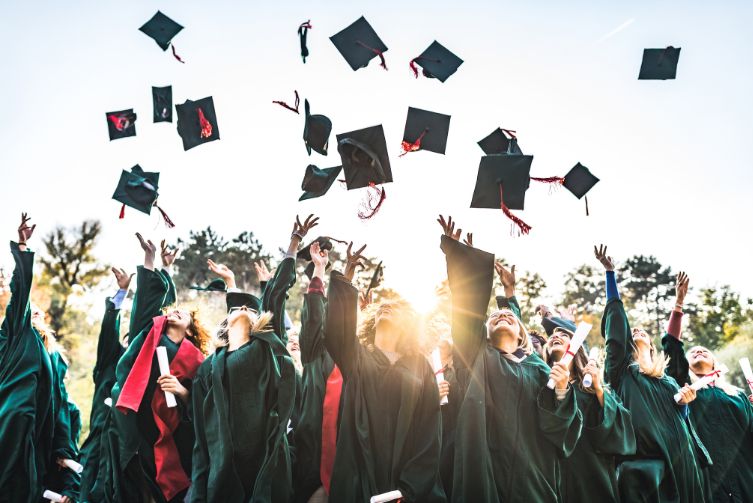 A group of graduates throw their caps in the air.