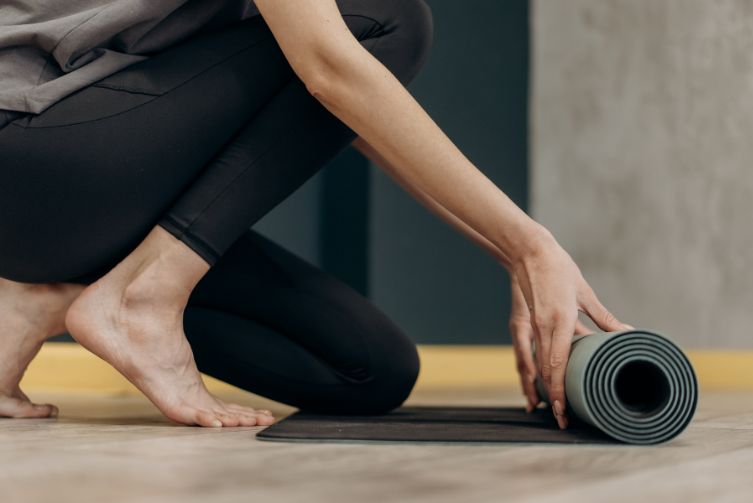 Woman rolls out yoga mat