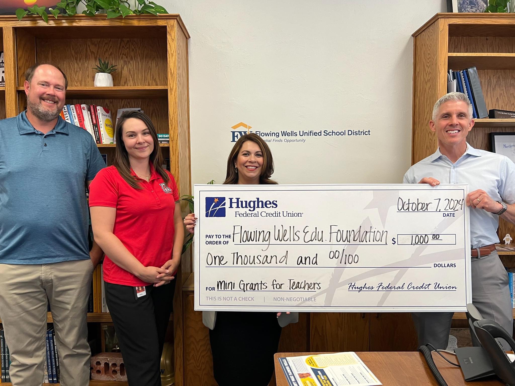 Four people stand with a giant check